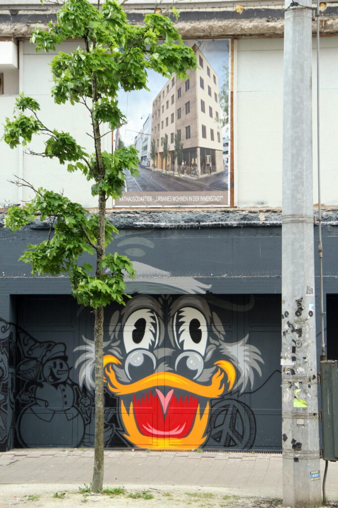 Grafito zeigt Donald Duck und darüber ein Bild von einem Wohnhaus